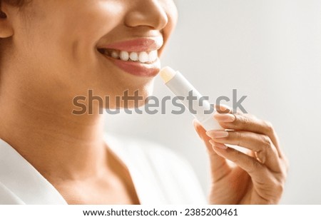 Lip Care. Unrecognizable young black woman applying moisturising chapstick on lips, closeup of smiling african american female using nourishing lip balm while making beauty routine at home, cropped Royalty-Free Stock Photo #2385200461