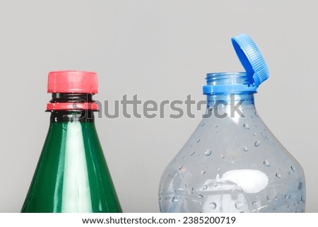Example of older model and new cap attached to plastic bottle, connected to the neck of the bottle by solid tab attached to safety ring.  Royalty-Free Stock Photo #2385200719