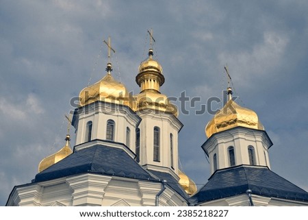 The golden domes of a Orthodox Church, standing majestically against a backdrop of a clear blue sky. Gilded domes of an ancient Orthodox church against the sky.
