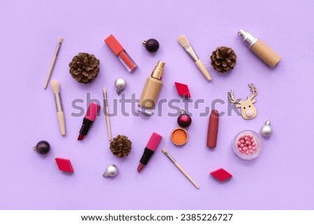 Different decorative cosmetics with Christmas balls and cones on lilac background