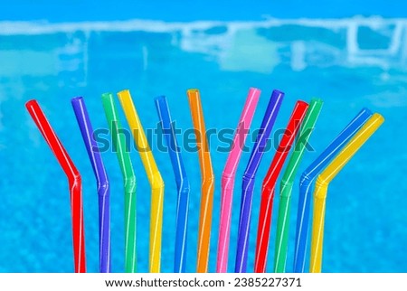 Cocktail straws against the background of a blue pool. Multi-colored cocktail straws are ready for the party.
