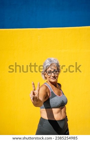 Mature woman in sports clothes gesturing number two with hands