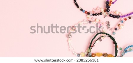 Banner with handmade bracelets made of beads and cords on a pink background. 