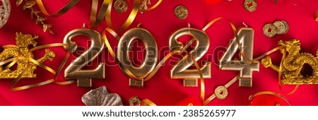 Chinese New Year 2024 greeting card. Bright red asian year of the dragon background with golden dragon figurine, Chinese lanterns, traditional jewelry, gifts, coins, cookies with wishes, copy space Royalty-Free Stock Photo #2385265977