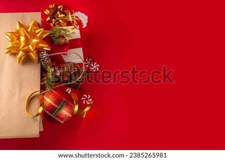 Christmas and New Year sale, shopping background, banner template. Bright red flat lay with paper shopping bag full of gifts, Christmas decorations, fir tree branches, with shopping and sale tags