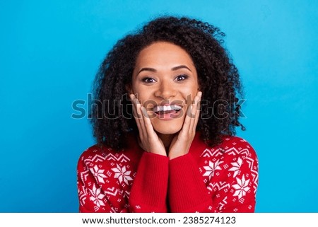 Portrait of excited girl dressed ugly red print pullover arms cheeks smiling shocked see santa claus isolated on blue color background