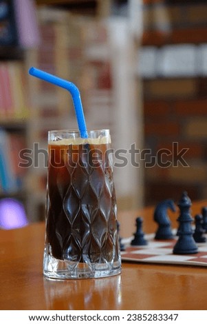 A glass of cola and chess on a table. Chess table in cafe