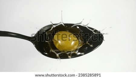 Green Olive, Olea europaea, Falling in a Spoon against White Background