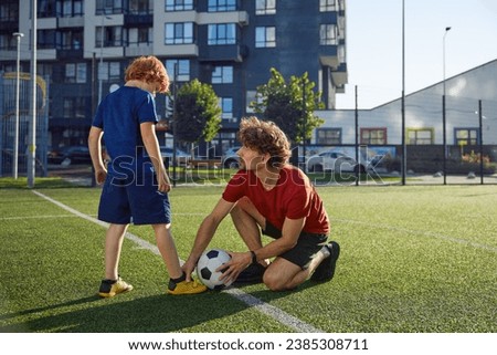 Father teaching son child to play football on city stadium Royalty-Free Stock Photo #2385308711
