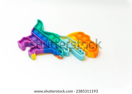 Rainbow dinosaur shaped pop it  toys or push pop fidget toys isolated on white background. Sensory Silicone Toys for Autism, Fidget Popper, Anti Anxiety and Stress Relief Game.  