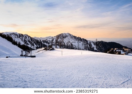 Ski resort and lodges on Klewenalp mountain in Swiss Alps, Switzerland. Popular ski slope and winter sport attraction, winter landscape with snow at sunset. Royalty-Free Stock Photo #2385319271