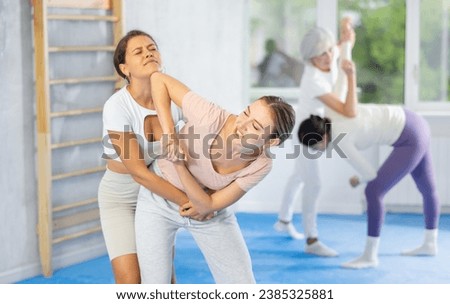 Group of women training to do painful hold in pairs during a self-defense class