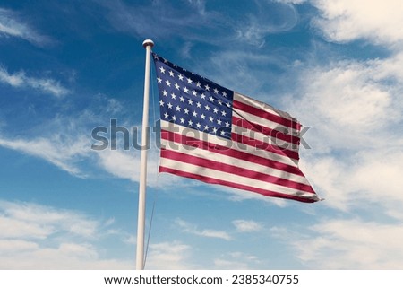 United States of America flag waving at cloudy sky background. USA flag.