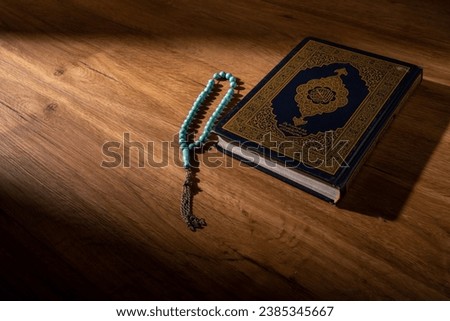 Islamic concept - The Holy Al Quran with written Arabic calligraphy meaning of Al Quran and rosary beads or tasbih, Arabic word translation: The Holy Al Quran (holy book of Muslim) 