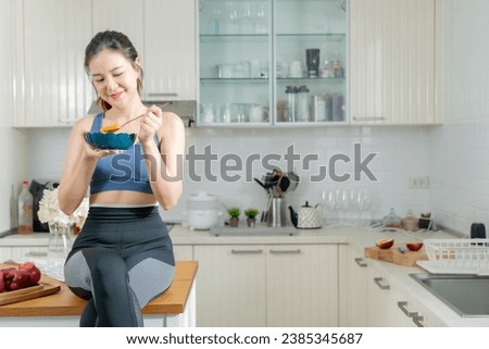 A healthy Asian woman in exercise clothes Is happily cooking a healthy meal in her home kitchen in the morning. Healthy care concept, Healthy fruits every day. Royalty-Free Stock Photo #2385345687