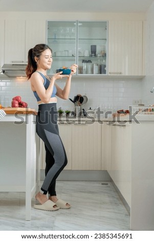 A healthy Asian woman in exercise clothes Is happily cooking a healthy meal in her home kitchen in the morning. Healthy care concept, Healthy fruits every day. Royalty-Free Stock Photo #2385345691