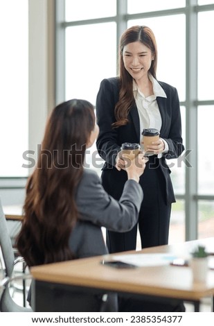 Asian professional successful female businesswoman supervisor mentor in formal suit standing, sitting smiling taking break drink coffee browsing tablet online in company office.