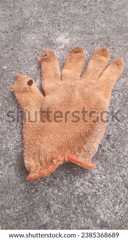 Brown gloves made from wool thread are seen above against a street texture background. concept background of fashion, cotton, fabric, healthcare, medical, personal protection, virus, health, business