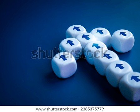 Leadership, go to success, business team progress, teamwork, advances in technology concept. Close-up straight arrows icon symbol on white dice block built as heading arrow shape on blue background. Royalty-Free Stock Photo #2385375779