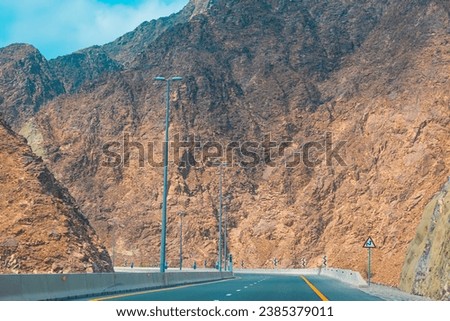 Fujairah mountains, extension of Omani Al Hajar mountain range. Cloudy winter day on empty street. High quality photo Royalty-Free Stock Photo #2385379011