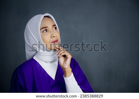 Asian hijab Nurse or Doctor wearing purple medical uniform, showing confidence body language with face expression.
