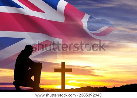 Poppy Day background. Remembrance Day. Man kneeling down before the grave cross. United Kingdom flag against the sunset