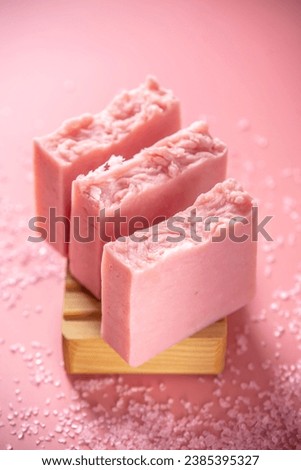 Cute pink pieces of organic eco soap on a soap dish made of natural wood on a pink background. Concept of modern and safe cosmetic products for skin care.