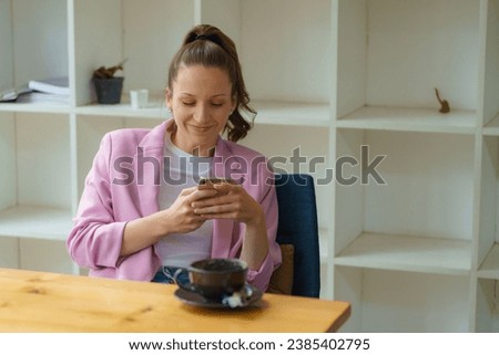 Attractive businesswoman looking on a smartphone while resting in an office during break time.