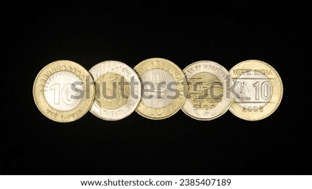 different variety of authentic ten and twenty rupee indian coins arranged in a horizontal row isolated in a black background Royalty-Free Stock Photo #2385407189
