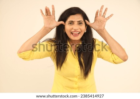 Indian funny woman with crazy expression posing in funny moods on using hands moments Isolated on studio background. funny facial expressions, shocking puffing cheeks with funny face. Mouth inflated  Royalty-Free Stock Photo #2385414927