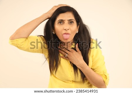 Indian funny woman with crazy expression posing in funny moods on using hands moments Isolated on studio background. funny facial expressions, shocking puffing cheeks with funny face. Mouth inflated  Royalty-Free Stock Photo #2385414931