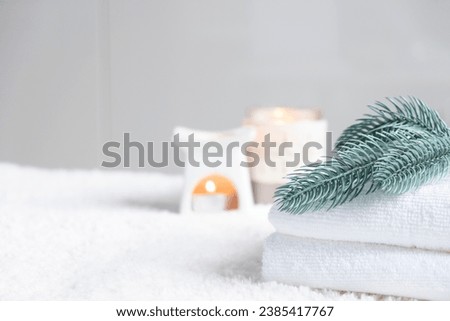 Fresh white towels with fir branch, candles and Christmas decorations. Wellness and wellbeing. SPA massage or beauty salon, relaxation and self care in Christmas or New Year variant. Copy space.