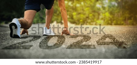 Male runner legs in starting position on road running into new year 2024, beginnings, goals and plans. Royalty-Free Stock Photo #2385419917