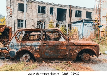 On the side of the road is a wrecked, burned-out civilian car. War in Ukraine. Russian invasion of Ukraine. War crimes Royalty-Free Stock Photo #2385425939