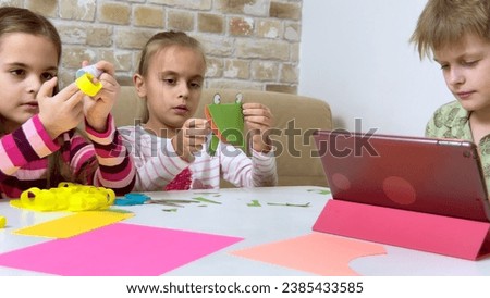 Two little girls and boy creating toys from colored paper and glue