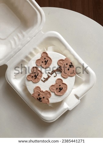 Bento cake for celebration day. A small cake with a picture or a congratulation for one person. A funny surprise dessert for a loved one. Cake with the head teddy bear.