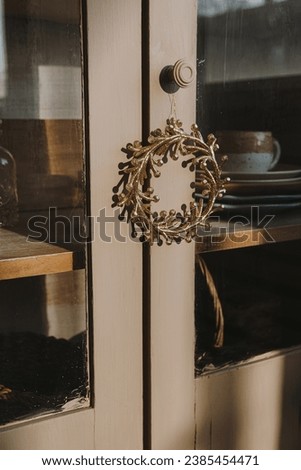 Gold Christmas wreath hanging on sideboard doors. New Year and winter holidays. Aesthetic Christmas decor