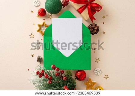 Wish list to Santa Claus takes center stage in this top view photo, complete with gift box, ornaments, frosty pine branch, holly berries, candles all set against soft beige background with text space