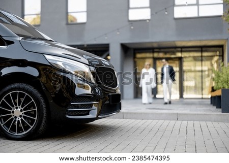 Business people walk to minivan taxi from office building. Concept of business trips and transportation service Royalty-Free Stock Photo #2385474395