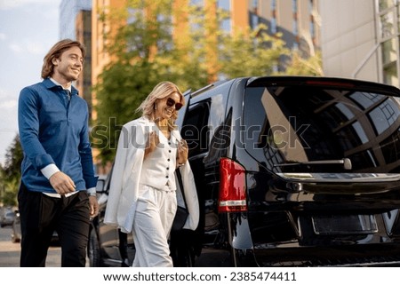 Business people get out of a minivan taxi, during a business trip by car. Concept of business trips and transportation Royalty-Free Stock Photo #2385474411