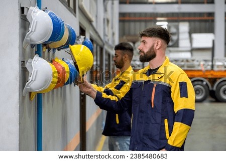 Two people are working in a factory. They are wearing construction hardhat on their heads for safety. Concept of work safety. Building industry.