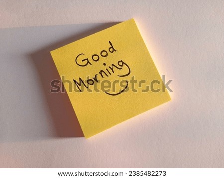 Yellow sticky note with text 'good morning', smile on white background, sun light coming from one side,with copy space