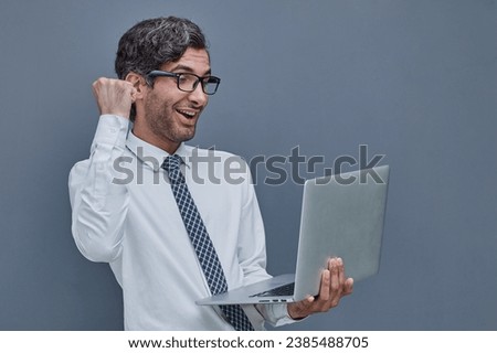 young successful man on a gray background typing in a laptop. surprised