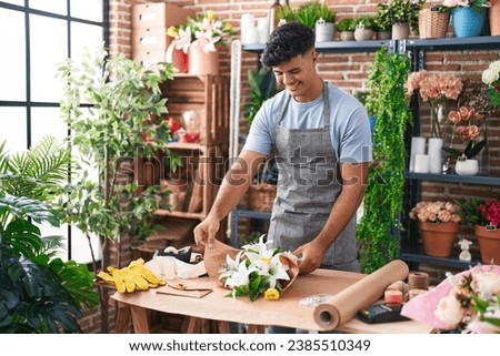 Young hispanic man florist make bouquet of flowers at flower shop Royalty-Free Stock Photo #2385510349