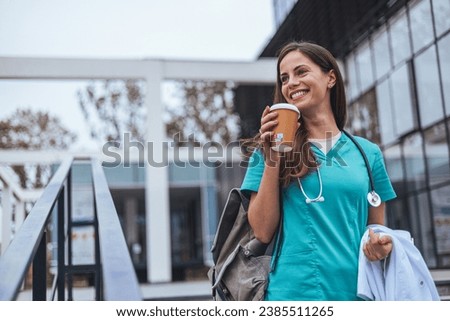 Hardworking mid adult beautiful nurse climbs the stairs to her apartment after a hard day at work. Portrait of happy young female nurse. A female healthcare worker leaving the house in her uniform.