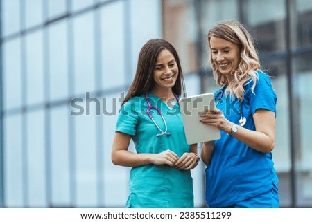 Researching news on a specific disease. Shot of two medical practitioners using a digital tablet together in a hospital. Healthcare staff having discussion in a hallway of private clinic.