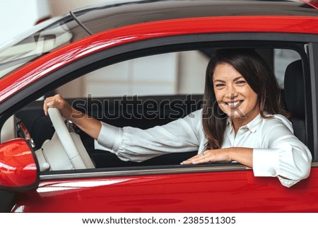 Young and cheerful woman enjoying . Woman driving a new car. Woman Driver Portrait at Car. Photo of happy young mixed race woman sitting inside her new car. Concept for car rental