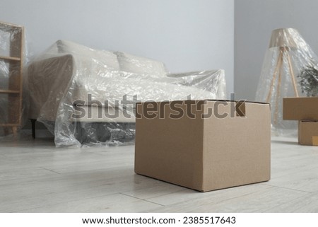 Modern furniture covered with plastic film and boxes at home Royalty-Free Stock Photo #2385517643