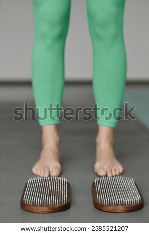 Vertical closeup of sadhu nail board on floor in yoga studio with young woman ready to step on