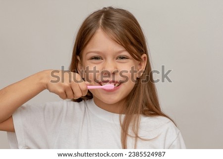 Portrait of caucasian happy little girl with open wide smile holding tooth brush near teeth looking at camera on white background